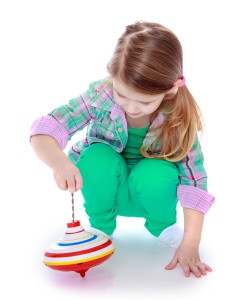 Happy childhood, the family concept.pretty little girl playing with a spinning top.Isolated on white.